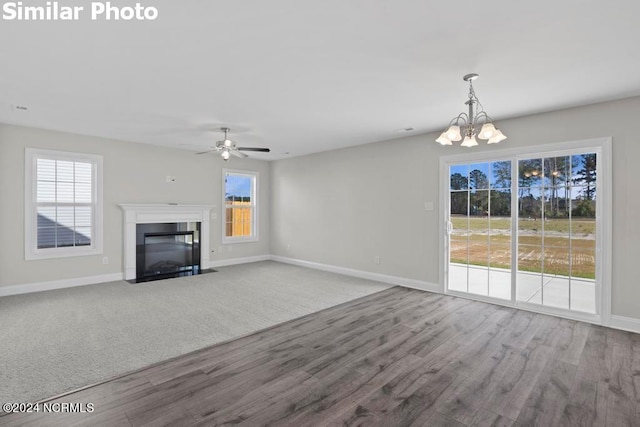 unfurnished living room featuring hardwood / wood-style floors and ceiling fan with notable chandelier