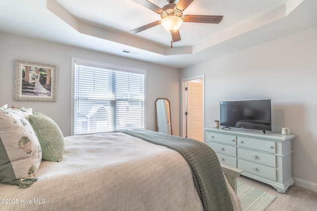 carpeted bedroom featuring ceiling fan and a raised ceiling