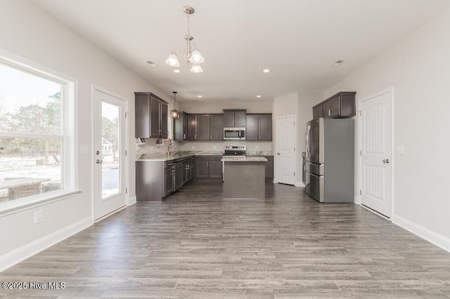 kitchen featuring a center island, dark brown cabinets, hardwood / wood-style flooring, pendant lighting, and stainless steel appliances