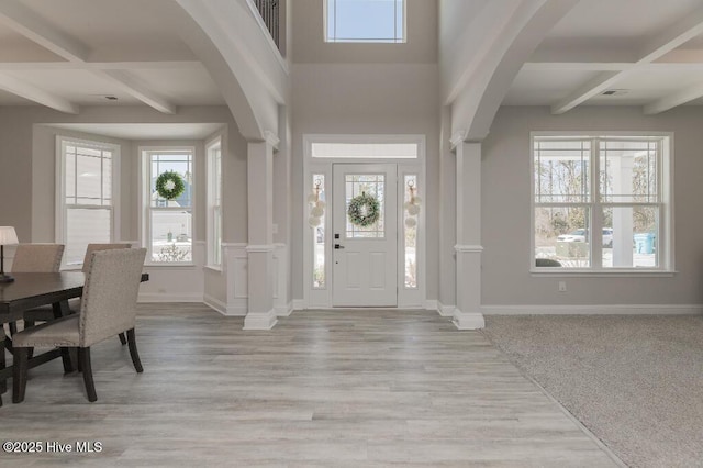 foyer featuring beamed ceiling, a healthy amount of sunlight, and light hardwood / wood-style floors