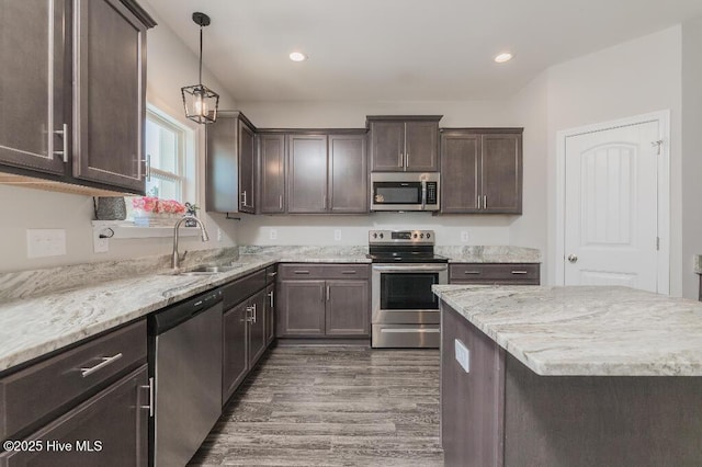 kitchen featuring pendant lighting, sink, dark brown cabinets, stainless steel appliances, and dark hardwood / wood-style floors