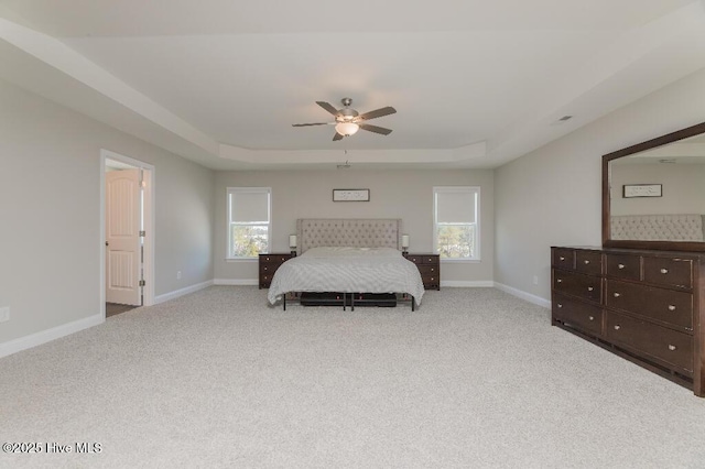 carpeted bedroom featuring multiple windows, a raised ceiling, and ceiling fan