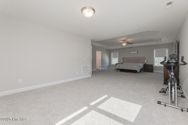 unfurnished bedroom with ceiling fan, a tray ceiling, and carpet