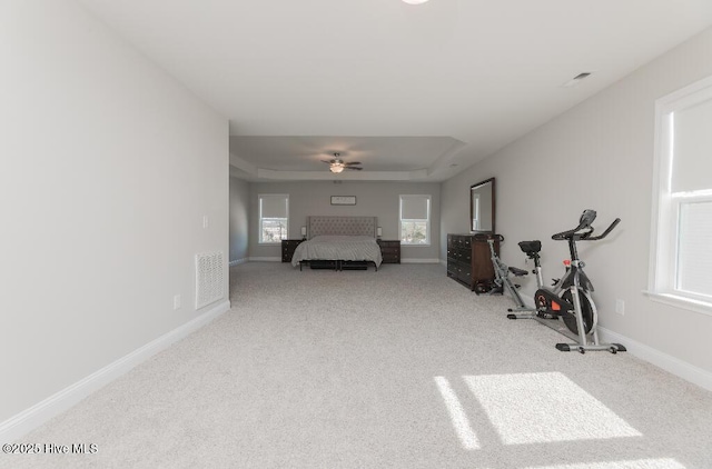 carpeted bedroom with a tray ceiling and ceiling fan