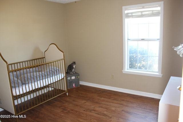 bedroom with dark hardwood / wood-style floors and a crib