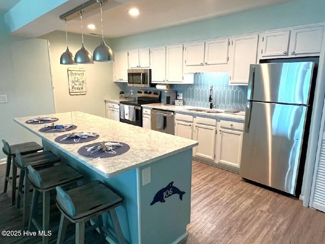 kitchen with white cabinetry, hanging light fixtures, sink, and appliances with stainless steel finishes