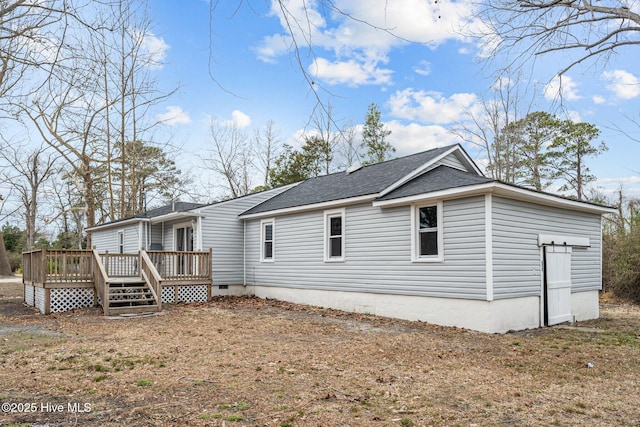 rear view of house featuring a wooden deck and a lawn