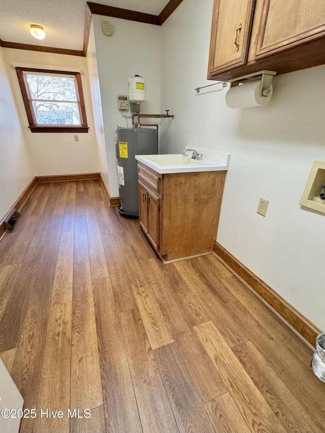 laundry room with cabinets, light hardwood / wood-style flooring, ornamental molding, hookup for a washing machine, and water heater