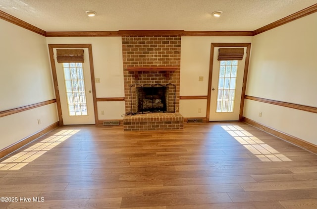 unfurnished living room with ornamental molding, light hardwood / wood-style floors, and a brick fireplace