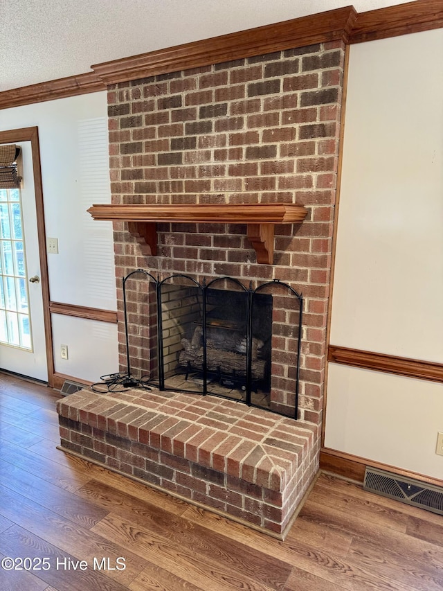 details featuring hardwood / wood-style floors, crown molding, a fireplace, and a textured ceiling