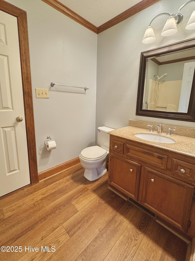 bathroom featuring ornamental molding, hardwood / wood-style floors, vanity, and toilet