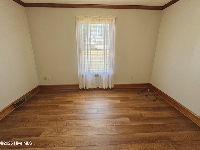 empty room with crown molding and hardwood / wood-style floors