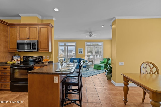 kitchen featuring black range with electric cooktop, crown molding, light tile patterned floors, and a kitchen bar