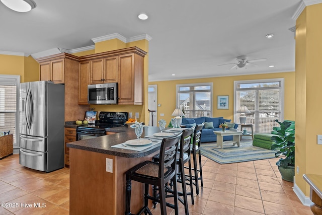 kitchen featuring light tile patterned floors, a breakfast bar area, ornamental molding, and appliances with stainless steel finishes