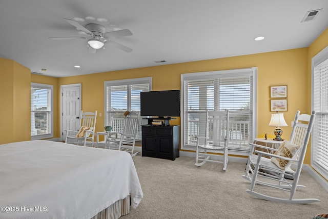 bedroom with ceiling fan, light colored carpet, and multiple windows