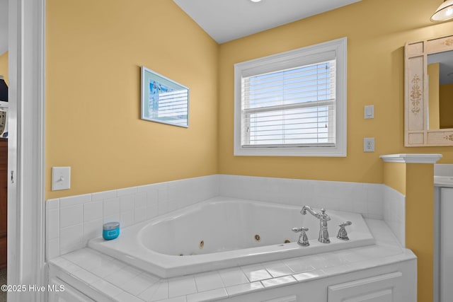 bathroom with vanity, a healthy amount of sunlight, and a relaxing tiled tub