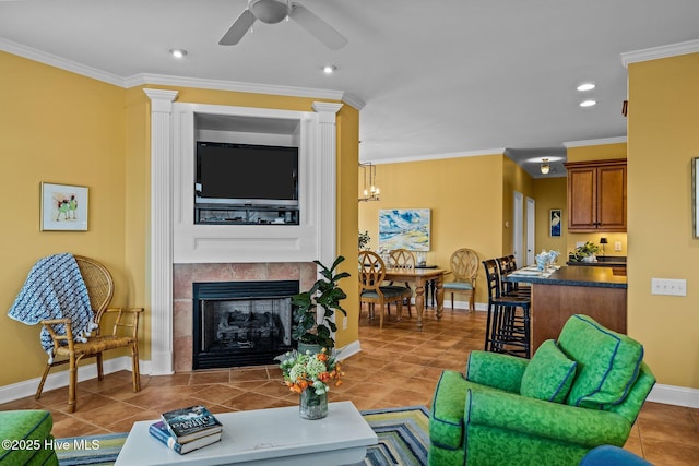 living room with ornamental molding, a tile fireplace, ceiling fan, and ornate columns