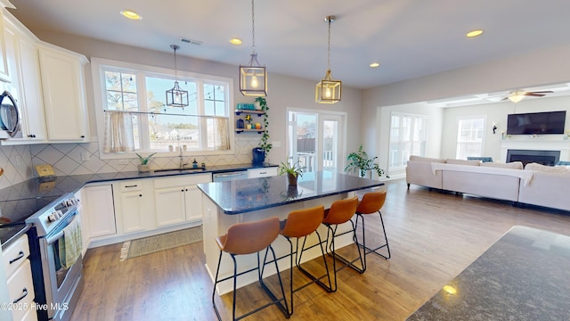 kitchen with a kitchen bar, a center island, light wood-type flooring, appliances with stainless steel finishes, and white cabinets