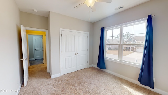 unfurnished bedroom with light carpet, ceiling fan, and a closet