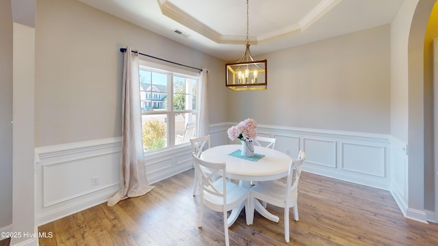 dining room featuring light hardwood / wood-style flooring, ornamental molding, a raised ceiling, and a chandelier