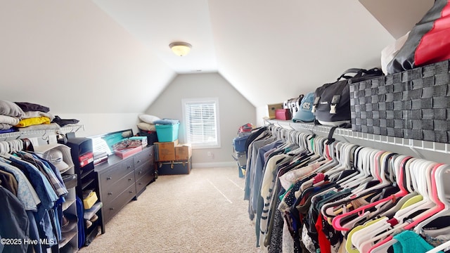 walk in closet with lofted ceiling and light carpet