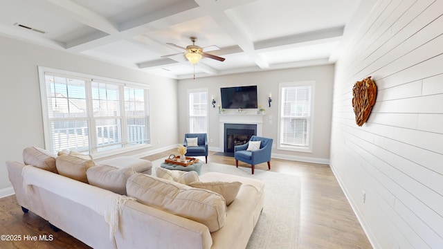 living room with beam ceiling, ceiling fan, coffered ceiling, and light hardwood / wood-style floors