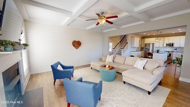 living room with coffered ceiling, a notable chandelier, beam ceiling, and light wood-type flooring