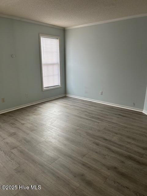 empty room with crown molding, dark hardwood / wood-style floors, and a textured ceiling