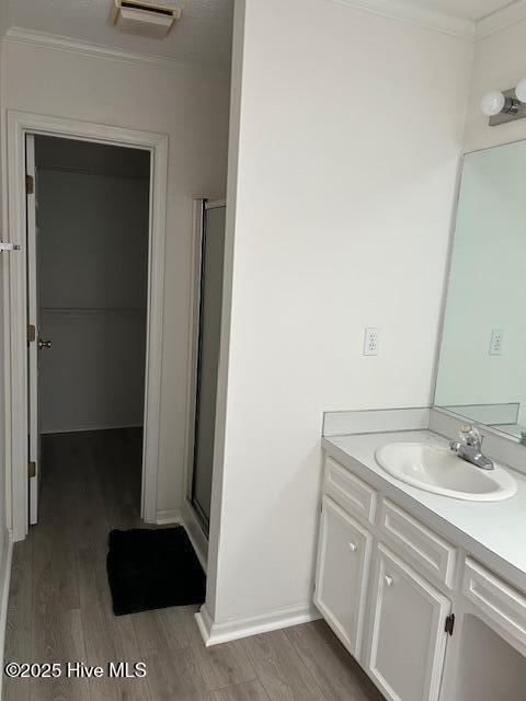 bathroom featuring a shower with door, crown molding, wood-type flooring, and vanity