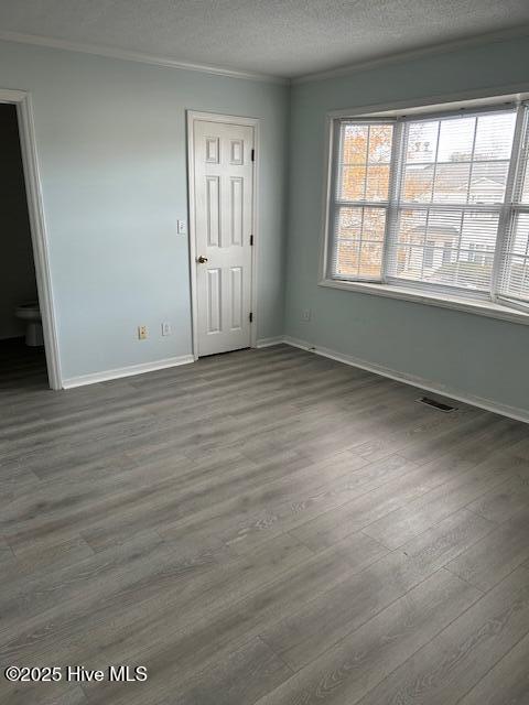 empty room featuring crown molding, hardwood / wood-style floors, and a textured ceiling