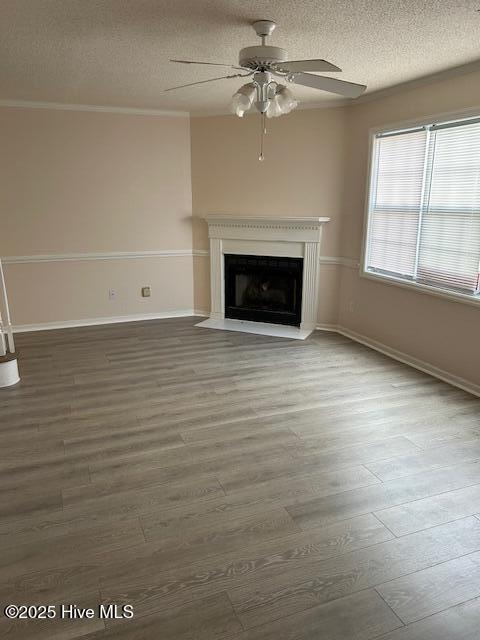 unfurnished living room featuring crown molding, ceiling fan, wood-type flooring, and a textured ceiling