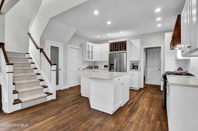 kitchen with dark hardwood / wood-style floors, white cabinetry, sink, stainless steel appliances, and a center island with sink