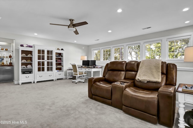 home theater room with ceiling fan and light carpet