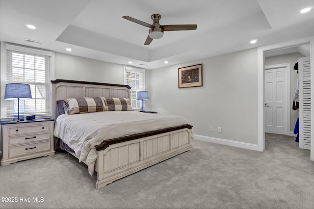 carpeted bedroom featuring a tray ceiling and ceiling fan