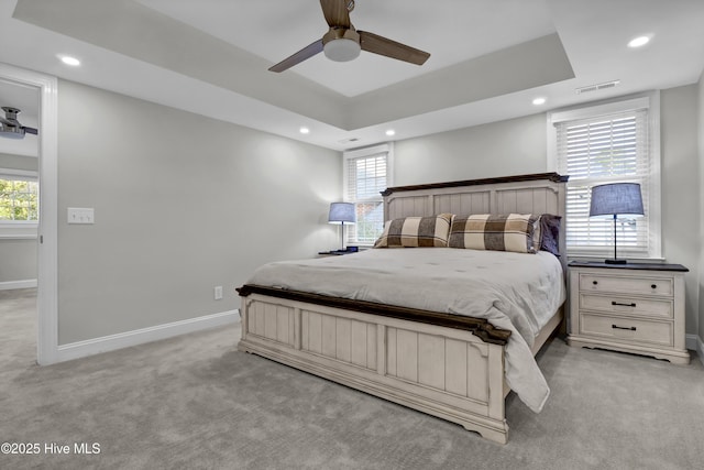 carpeted bedroom featuring ceiling fan and a raised ceiling