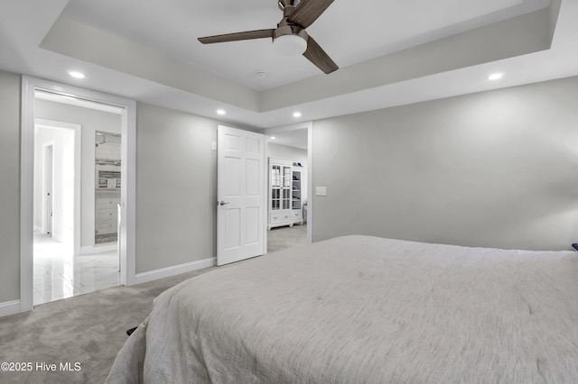 carpeted bedroom featuring ceiling fan and a raised ceiling