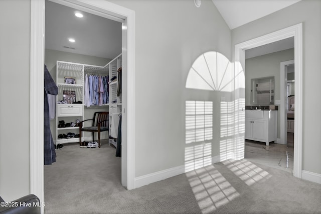 corridor featuring light carpet, sink, and vaulted ceiling