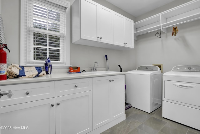 washroom with sink, washing machine and dryer, and cabinets