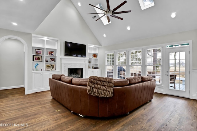 living room with a premium fireplace, a healthy amount of sunlight, dark hardwood / wood-style floors, and a skylight