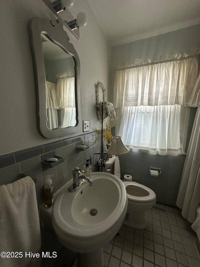 bathroom featuring tile walls, sink, tile patterned flooring, and toilet