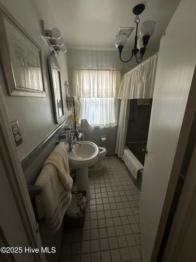 bathroom featuring an inviting chandelier, toilet, tile patterned flooring, and shower / bath combo with shower curtain