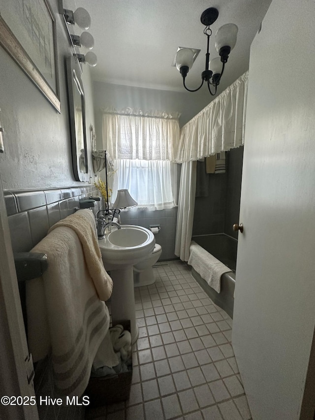 bathroom featuring tile patterned floors, a chandelier, toilet, and shower / bath combo with shower curtain