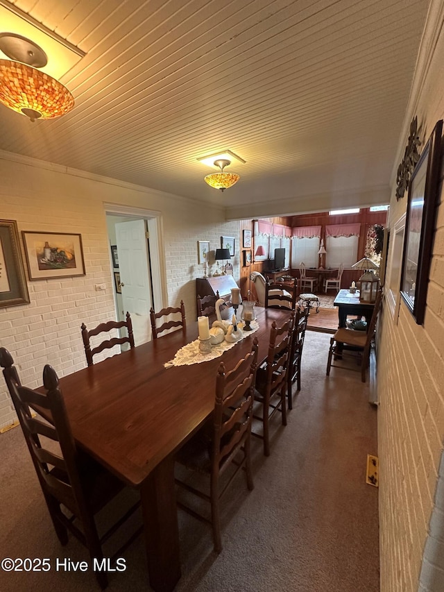 dining area featuring carpet floors, wooden ceiling, and brick wall