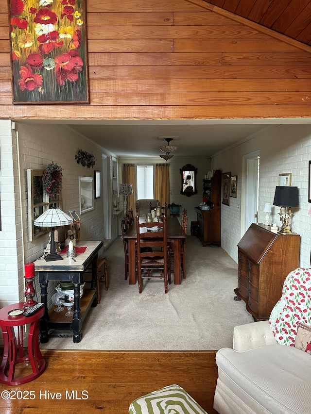 dining room with ornamental molding, brick wall, and carpet floors