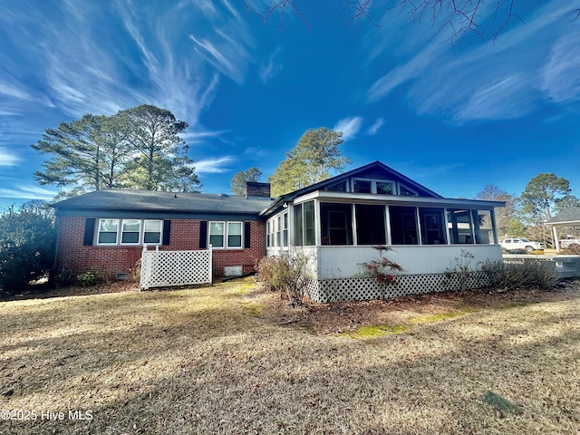 rear view of house featuring a sunroom and a lawn