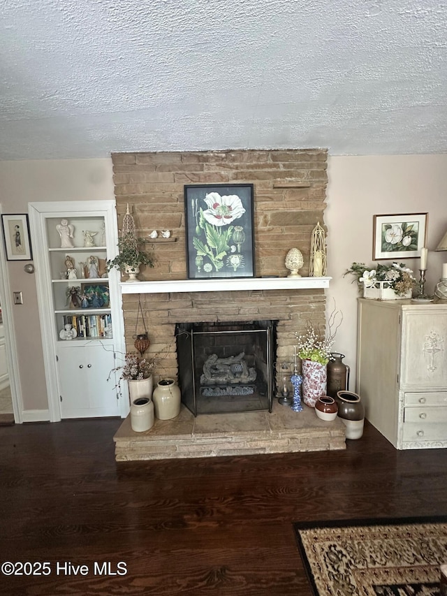 living room featuring dark wood-type flooring, a fireplace, and a textured ceiling