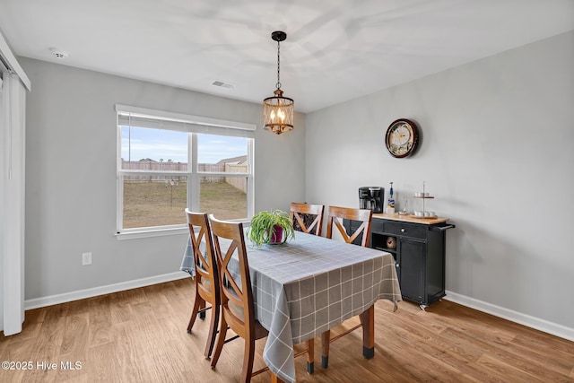 dining space with a notable chandelier and light hardwood / wood-style floors