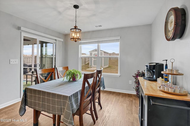 dining space with a healthy amount of sunlight, a notable chandelier, and light wood-type flooring