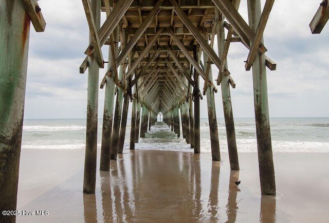 surrounding community featuring a pier, a beach view, and a water view