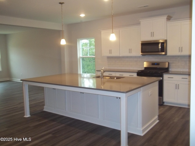 kitchen with an island with sink, a sink, backsplash, white cabinetry, and appliances with stainless steel finishes